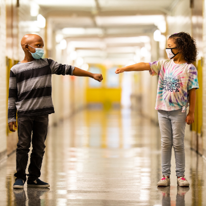 two students reaching out in school hallway